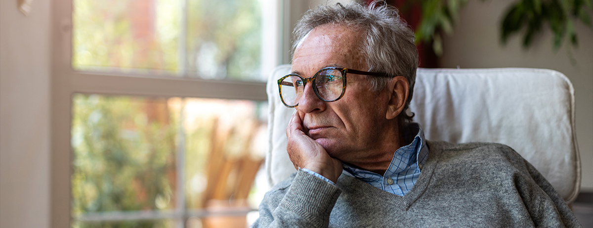 Sad man in glasses gazing out window