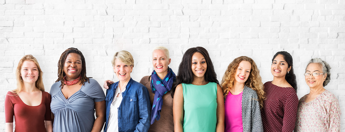 group of multicultural and multi aged women in a line against a brick wall