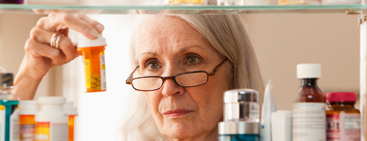 senior woman with glasses reading prescription pill containers