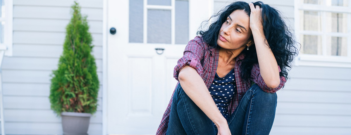 serious woman sitting on step in front of house