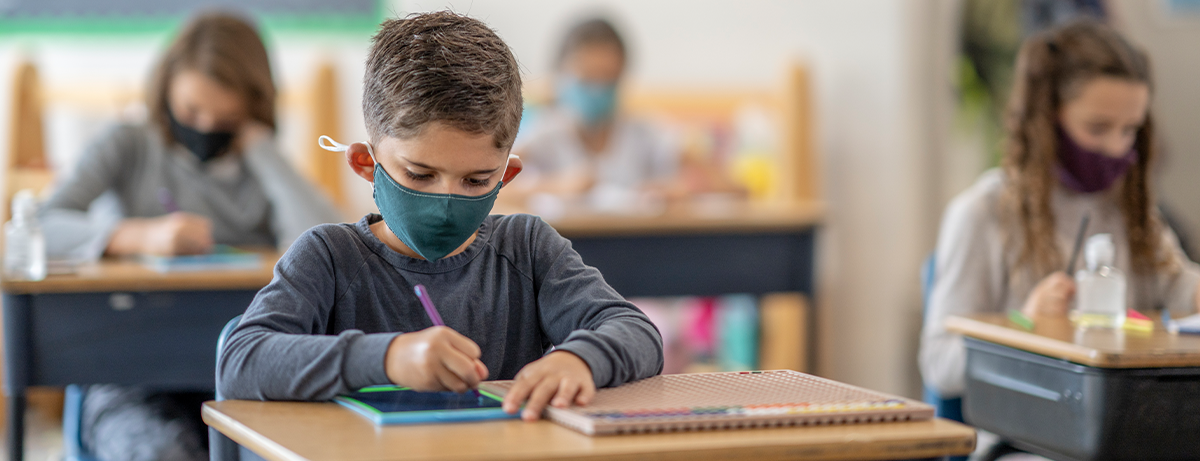 male student at desk wearing a mask