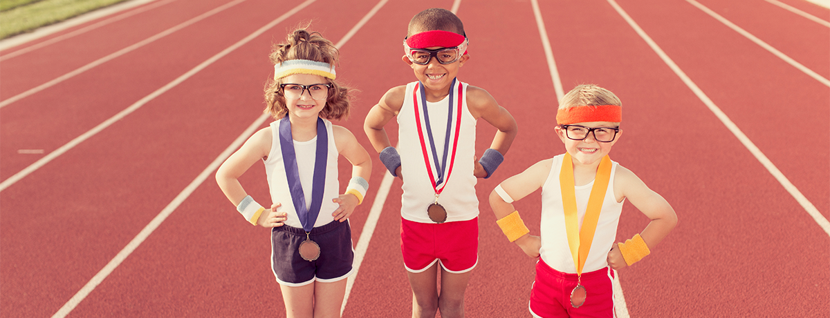 three kids dressed for exercise with awards on a track