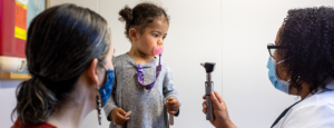 doctor and toddler sucking a pink pacifier