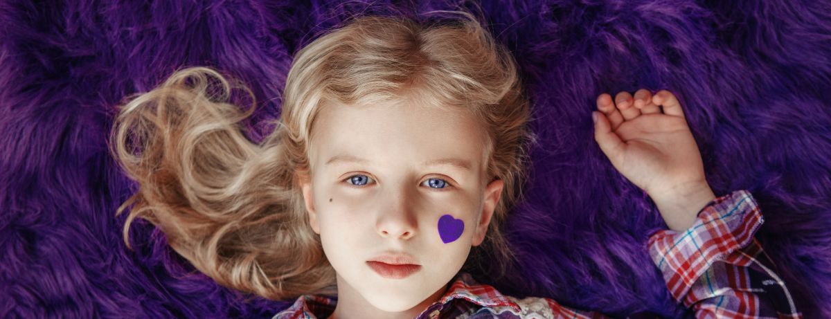 child laying on purple rug with heart on cheek