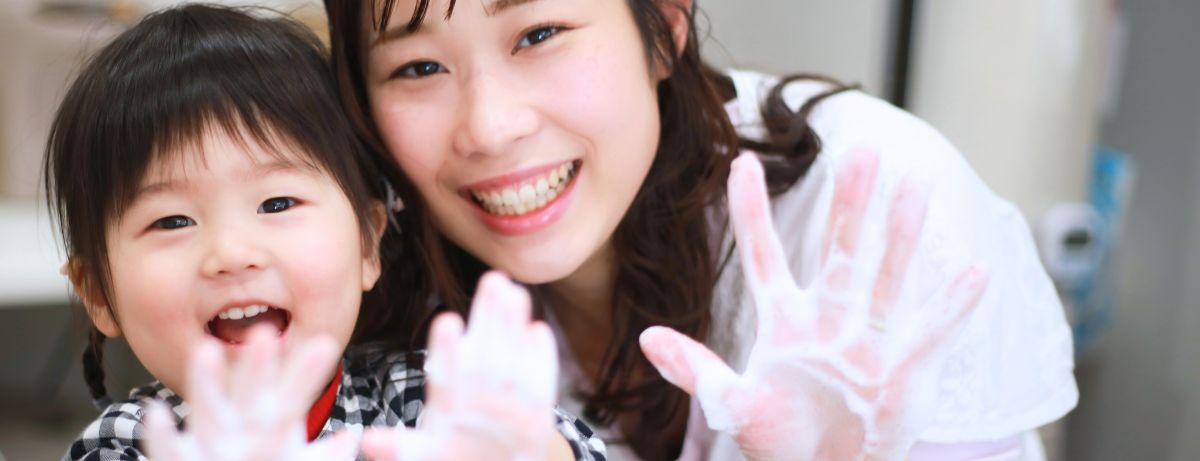 Asian mother and child holding up soapy hands